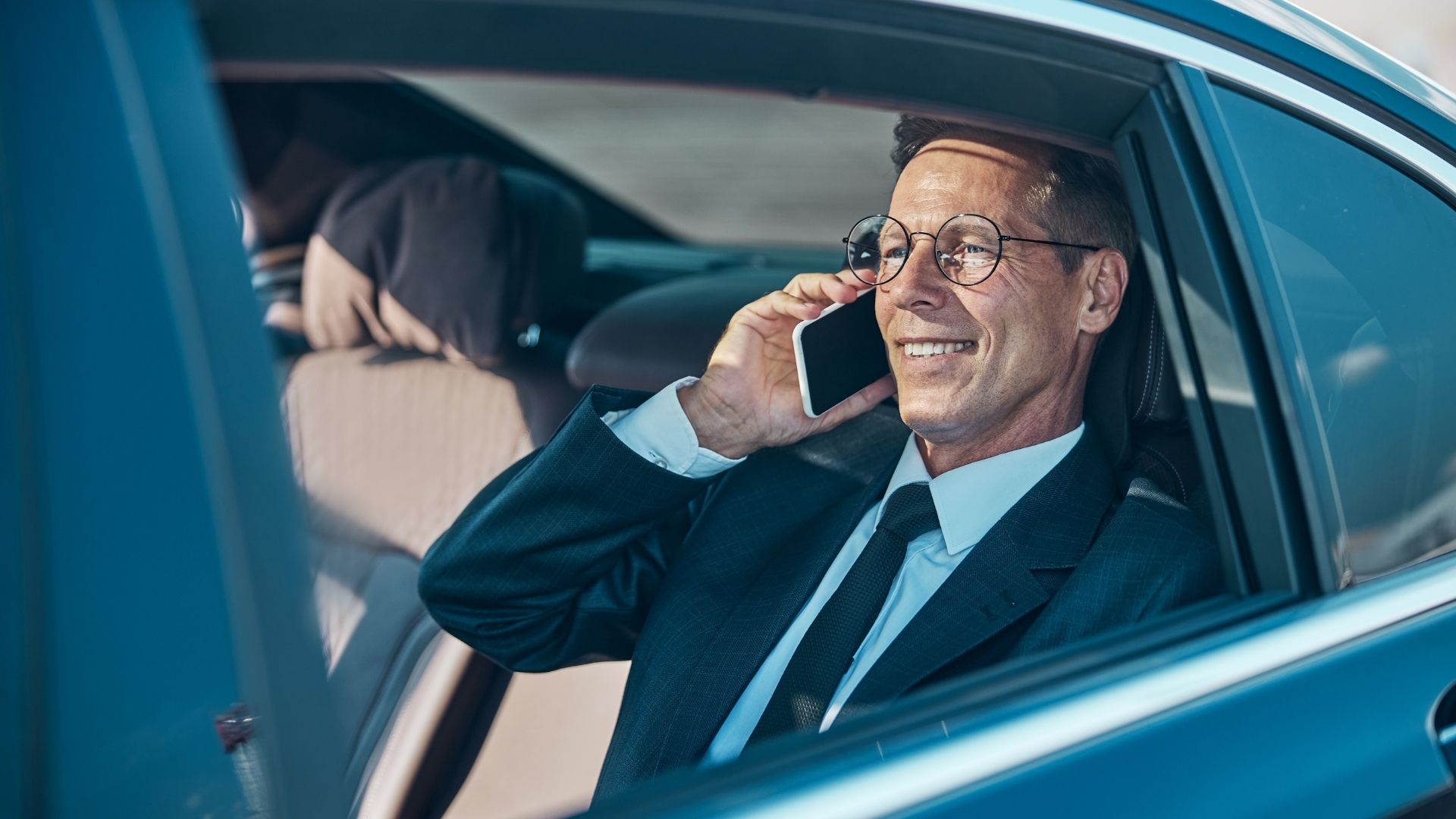 Executive passenger riding in the rear of a luxury chauffeured black car