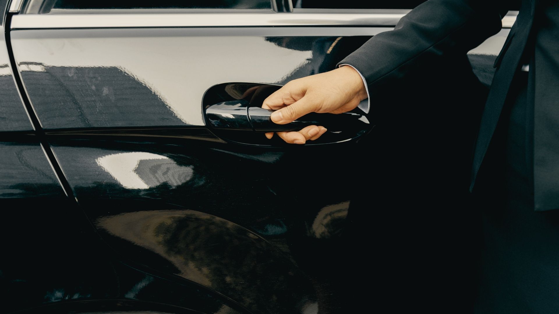 Chauffeur in uniform standing beside a luxury black vehicle